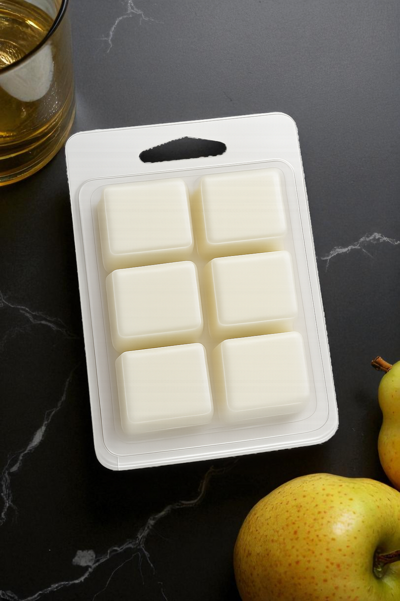 Packaged wax melts on a dark surface with golden pears.