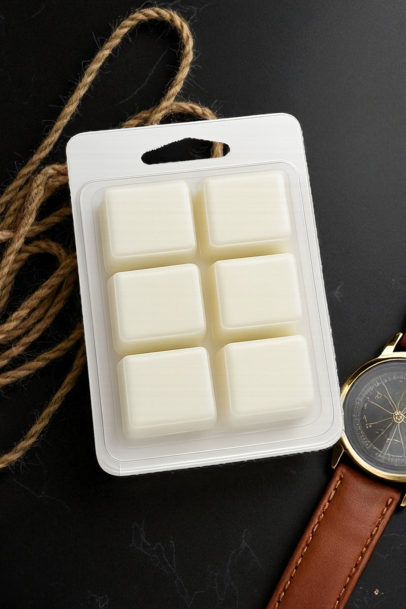 Pack of six white wax melts in a clear plastic packaging on a dark surface with a watch and rope.