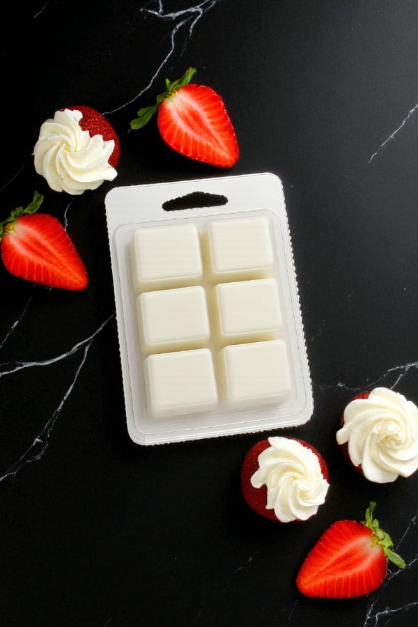 Packaged "Strawberry Poundcake" wax melts on a black surface with strawberries and cream.